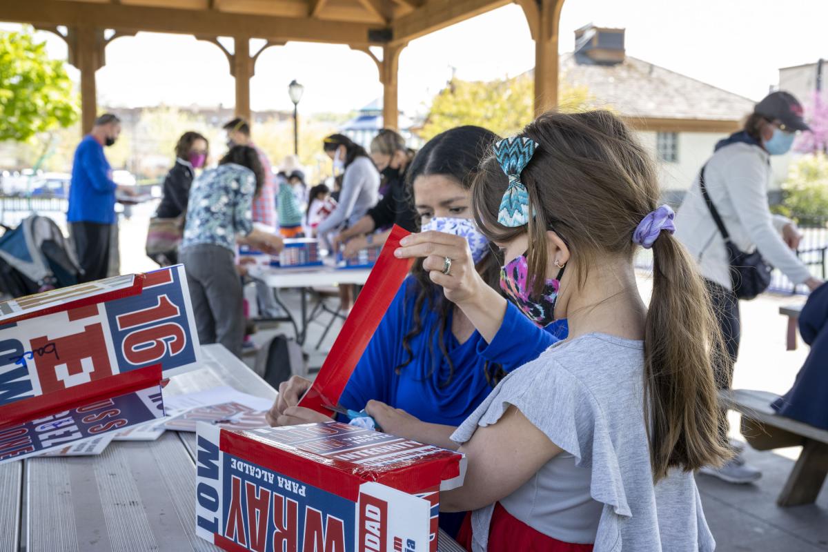 Two Girls Fold Paper Into Birdhouses