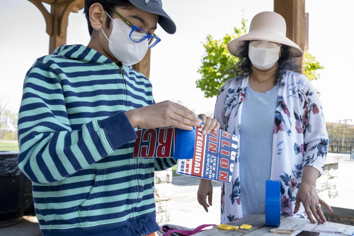 Boy with Glasses and Striped Shirt Folding Paper